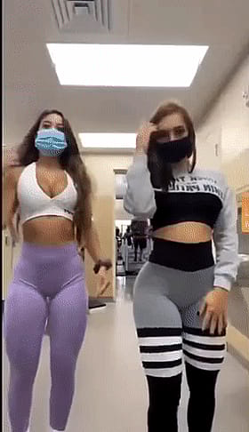 Two Hotties in Tights and Masks Walking Down the Hallway'