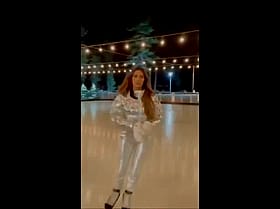 Brunette Celebrity in Silver Outfit Skating on Ice'